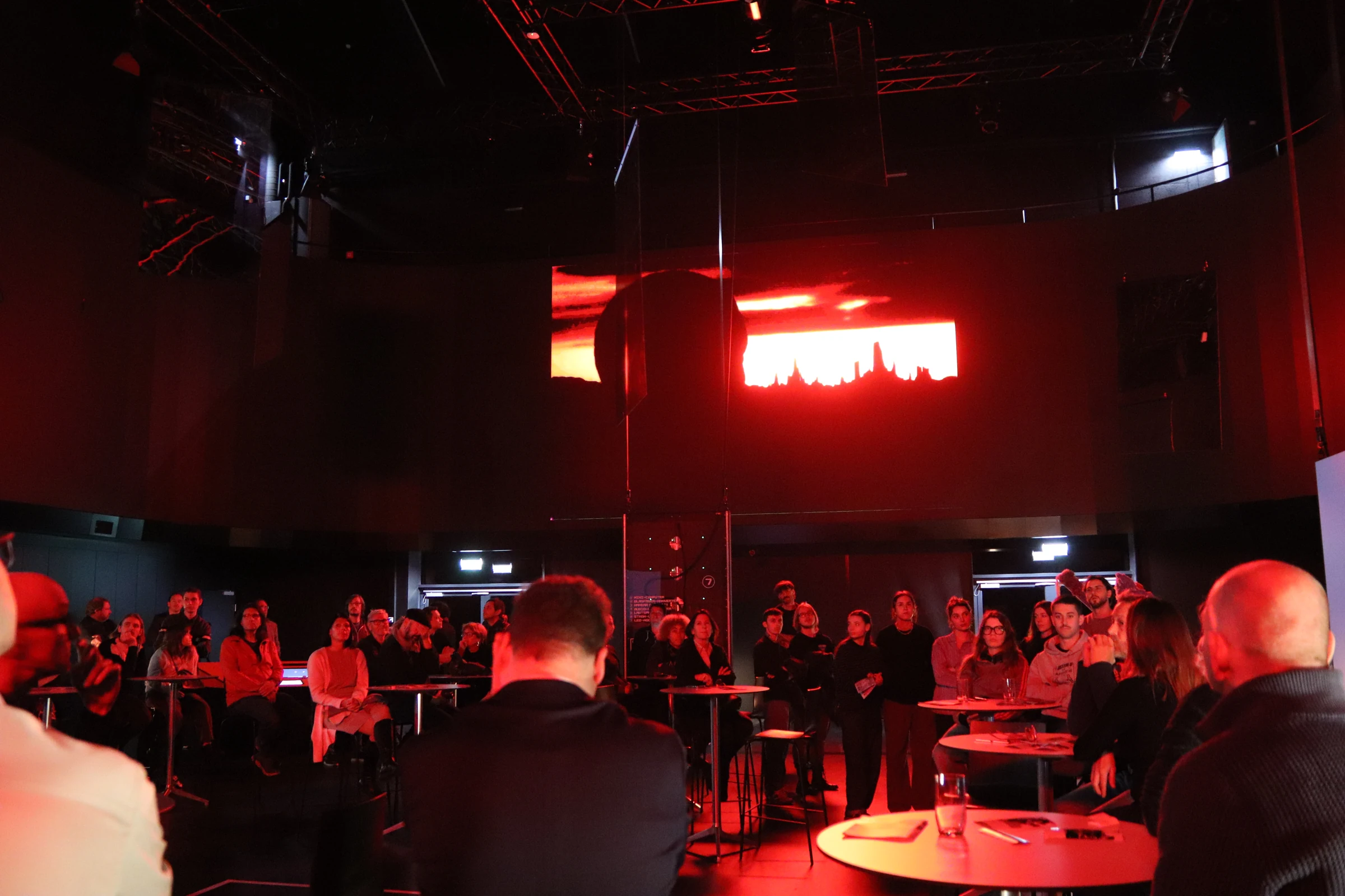 Publikum im rot beleuchteten Showroom